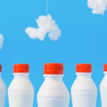 Three milk bottles with red caps under a cloud