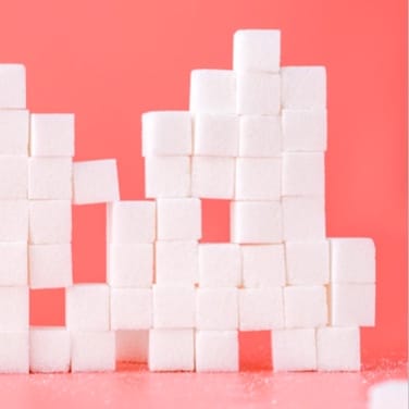A tower of sugar cubes on a pink background